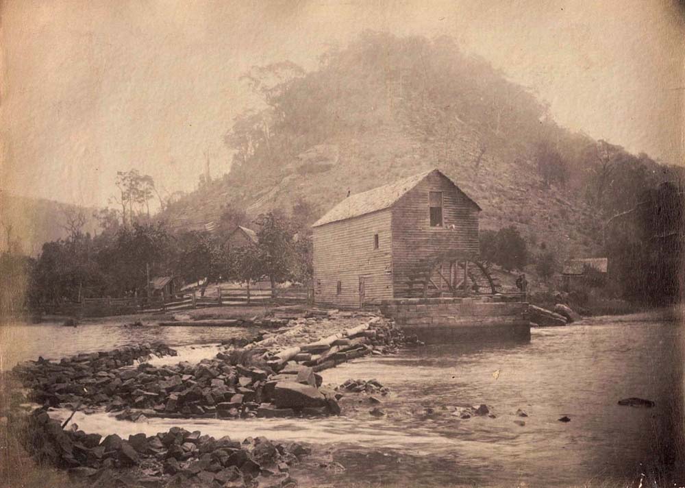 A photograph on an old postcard of Singletons Mill at Laybury Creek, Wisemans Ferry NSW, showing a section of crib wall and  flood damage to the mill pond wall